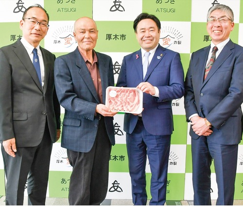 市内で生産されるブランド豚を手渡した