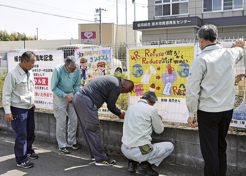 フェンスに絵を取り付ける職員ら