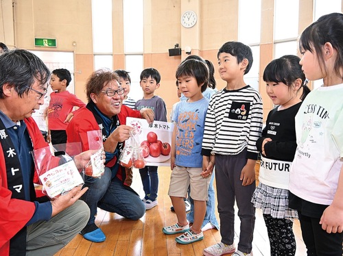 子どもたちにトマトを手渡す