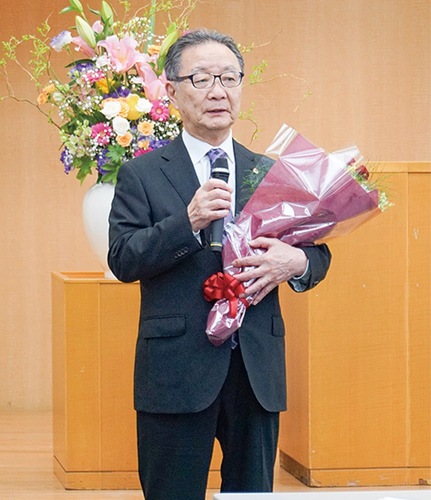 花束を手にあいさつする齊藤会長