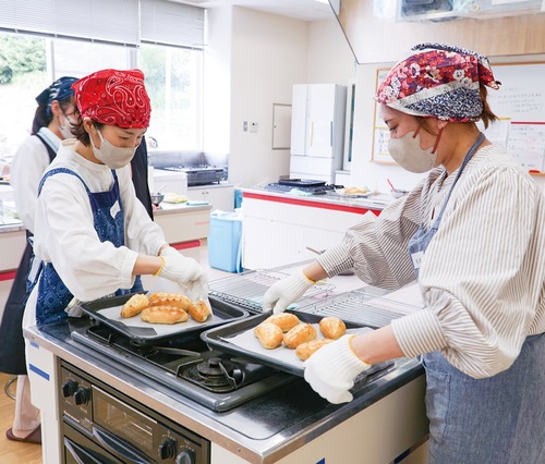 焼きたてのパンを天板から移す参加者