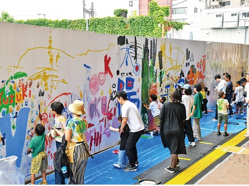 仮囲いに絵などを描く参加者