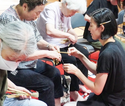 講師に習いながら真剣に箒を編む参加者