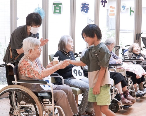 入居者と笑顔で握手をする小学生