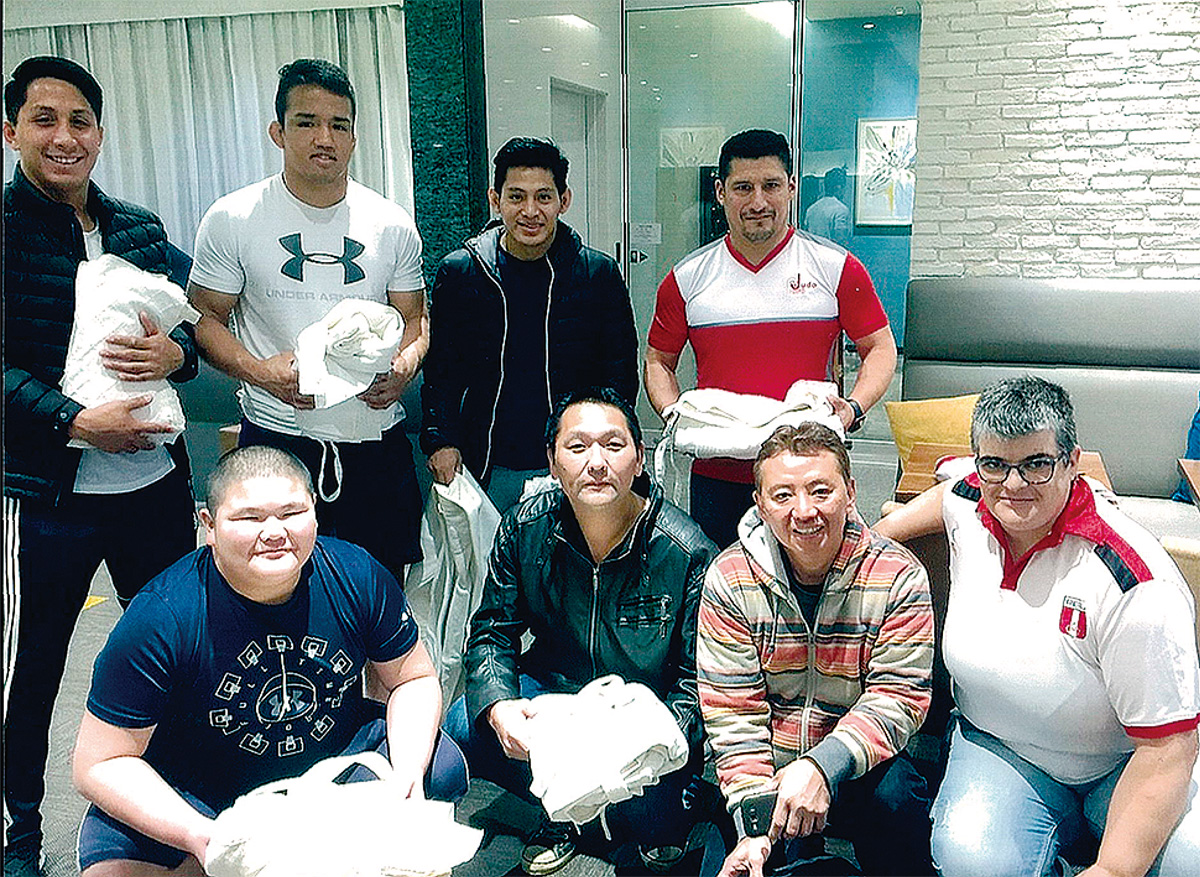 昨年12月に都内でペルー代表選手に柔道着を託す愛川町柔道協会の岩下会長（前列中央）ら