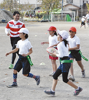 ボールを手に走る子どもたちと村田氏