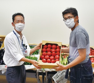 トマトを手渡す村田部長（右）