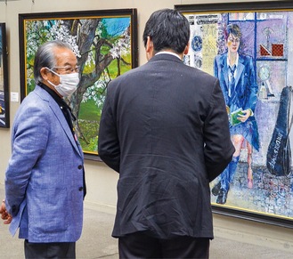 式典後に展示作品について解説する源馬会長（左）