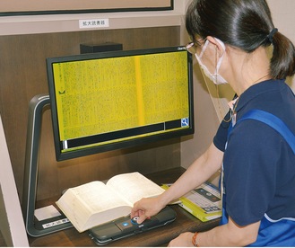 拡大読書器を操作する図書館職員
