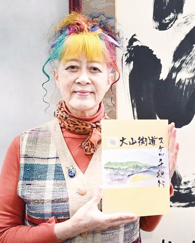 図録を手にする岡本さん（撮影／川崎市大山街道ふるさと館）