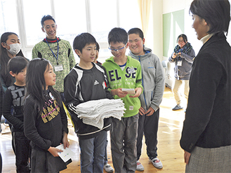 綱島さん(右)に絵手紙と雑巾を手渡す児童