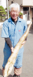 自分の背丈ほどの長芋を手に笑顔の澤村さん