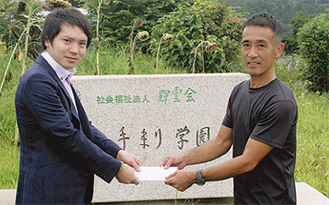 寄付金を手渡す岡田代表取締役（左）