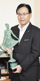 会長賞のブロンズ像を手にする平松理事長