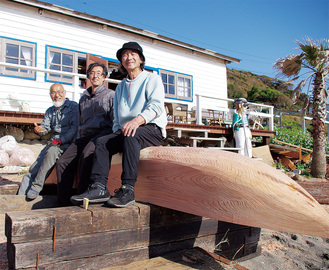 制作中のカヌーに座る（左から）土橋さん、豊岡さん、齋藤さん。矢作海岸のビーチハウスで