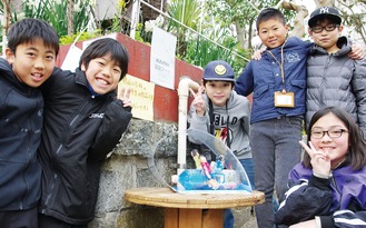 鴨居幼稚園前の作品を囲む４年生たち