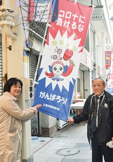 のぼり旗を広げるたちばなさん(左)と橋本理事長