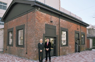 新施設の前で鹿島勇理事長（左）と眞鍋教授
