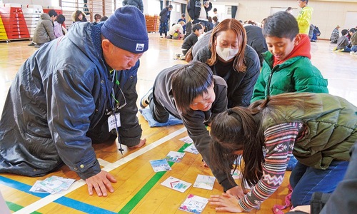 体育館でカルタを楽しむ児童と保護者ら