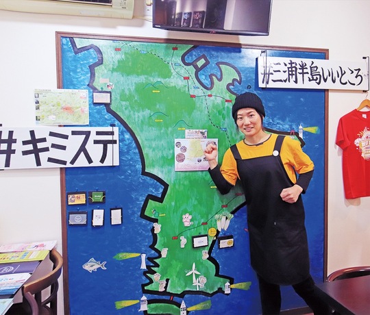 手製の三浦半島の地図を前にポーズする本間さん