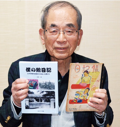 完成した冊子と当時の日記帳を手にする小川さん