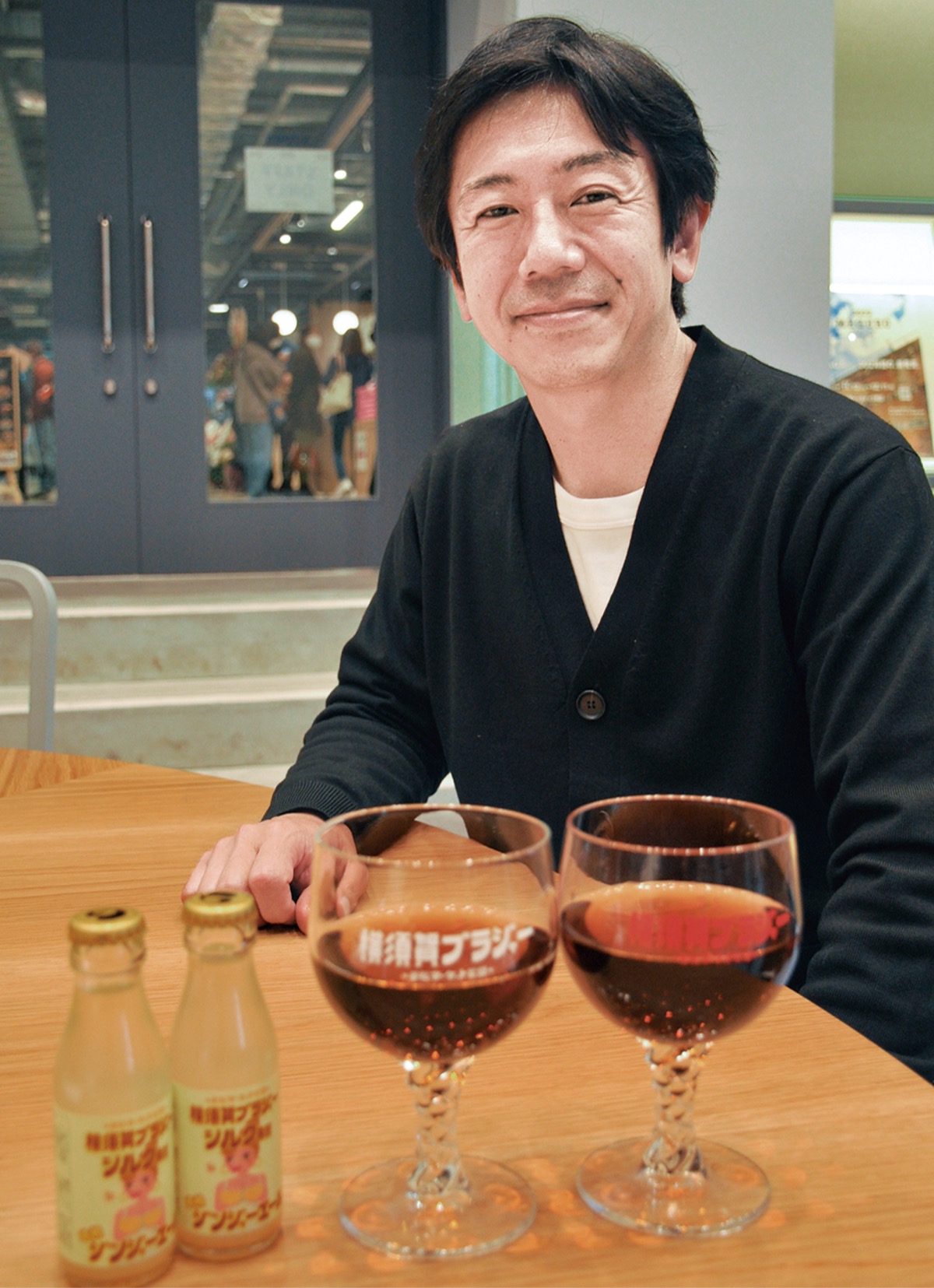横須賀ブラジャーを前に子安さん。専用グラス、派生商品も誕生した