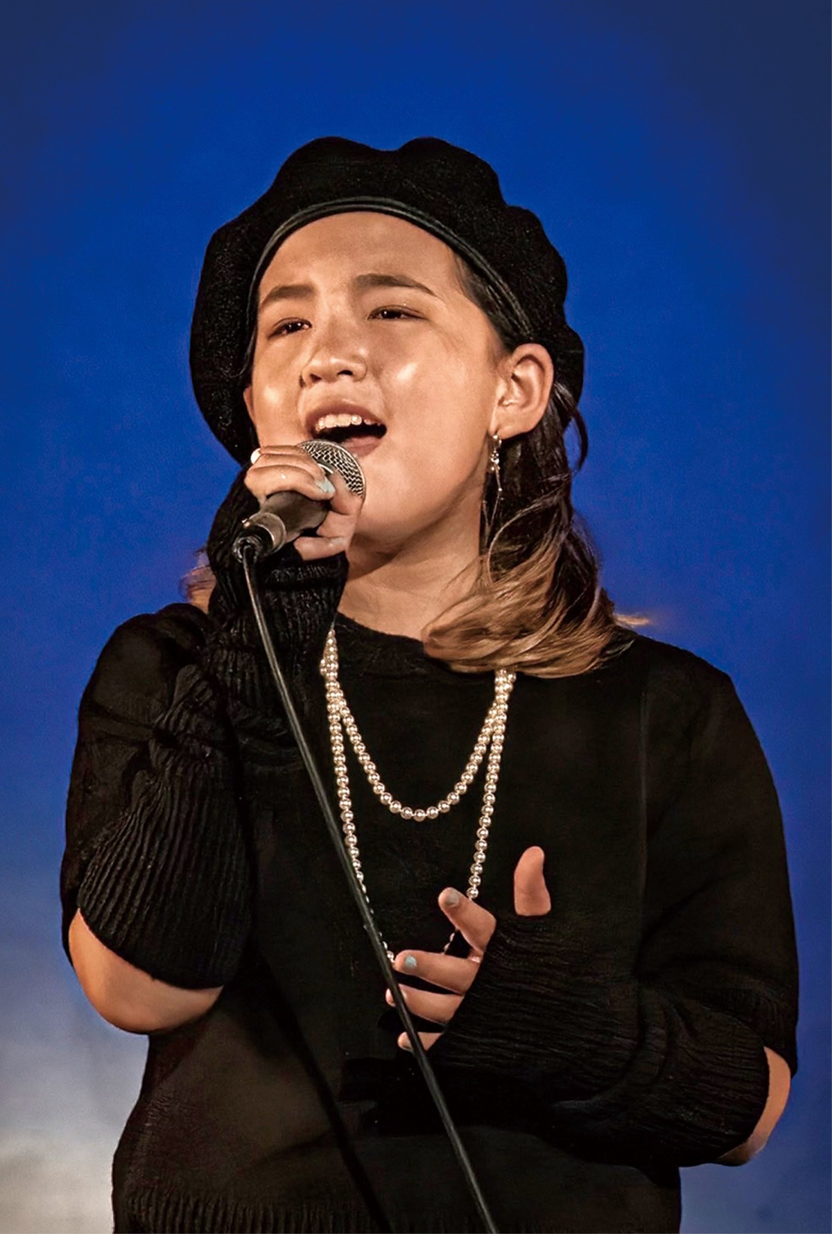 テレビ番組のコンテストで熱唱する莉愛さん=画像は家族提供