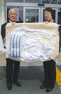 寝具セットを手にする青山会日景部長（右）と市社協熊谷副会長（左）