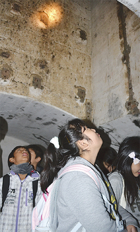 地下施設に掘られた立坑を見上げる児童ら
