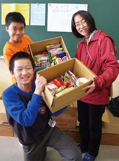 市社協の齋田聖子さん(右)に集まった食品を手渡した代表児童