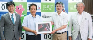 吉田市長（中央左）に寄贈品を手渡す石毛浩雄さん