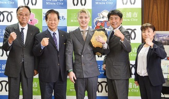 チャンピオンベルトを肩にかける里見選手（中央）と次大会での勝利を祈る吉田市長（左から２番目）、加藤会長（右から２番目）ら三浦ＲＣ会員たち