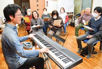 三崎ゴスペルサークルのメンバーに歌い方を指導する長谷川さん（左）＝３月18日夜、西海上会館