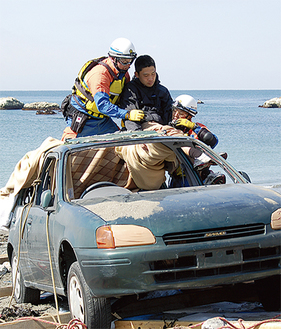 訓練で漂着した車両から負傷者を救出する消防隊員