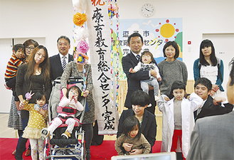 開所を祝って記念撮影する平井市長（後列右から3番目）と利用者ら（＝８日、桜山）