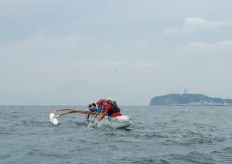 うっすらと浮かぶ富士山のシルエットに向かって漕ぐ子どもたち