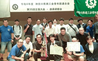 トロフィーと表彰状を持つ須藤さん（前列中央右）の応援に逗子葉山の仲間が駆けつけた（提供）