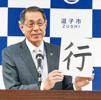 「行」の字を掲げる桐ケ谷市長