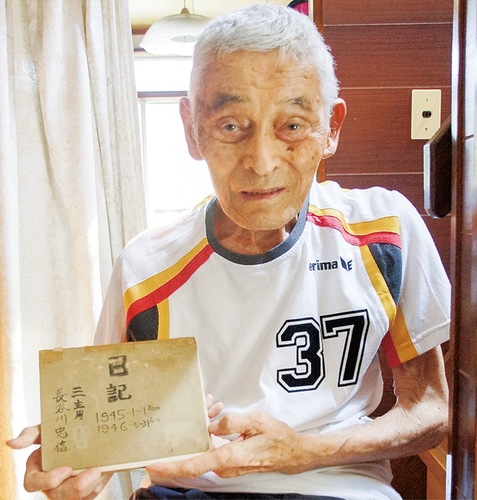 戦時中の日記を手にする長谷川さん