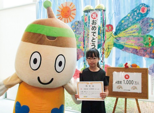 来館者1000万人目の認定証を持つ水島さん＝図書館提供