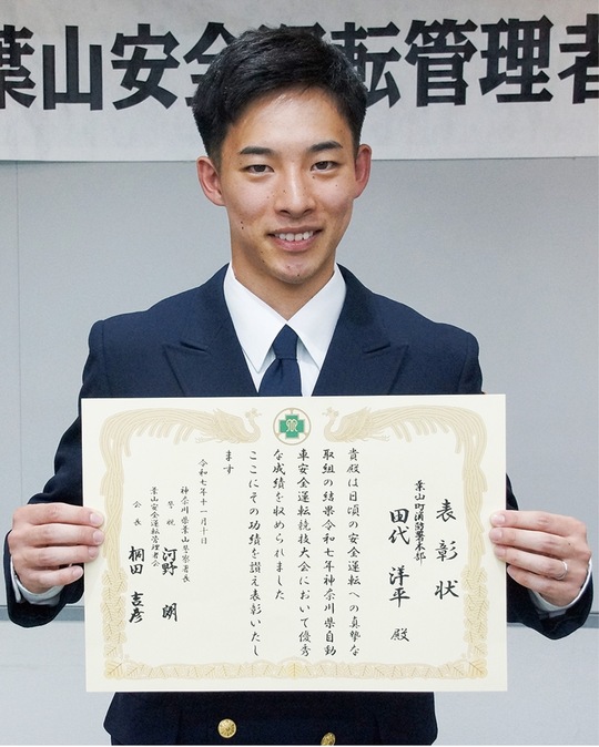 表彰状を手に笑顔を見せる田代さん