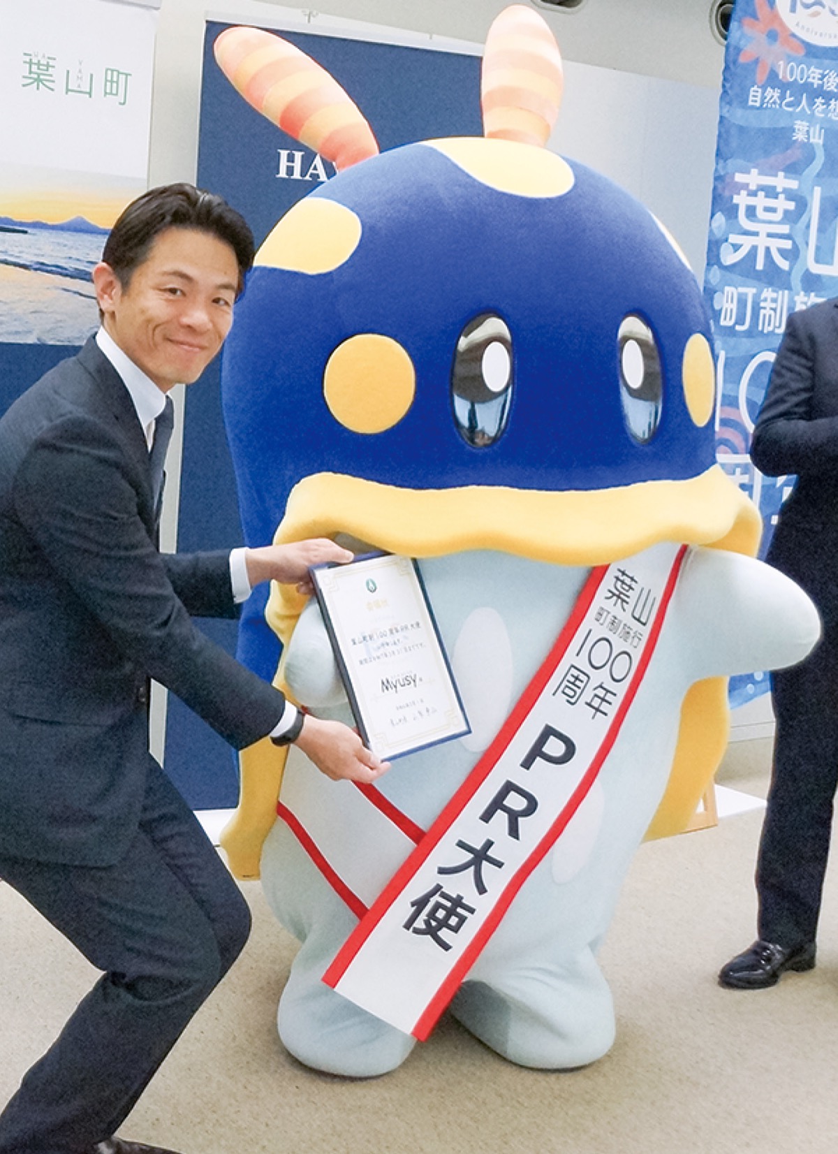 山梨町長から委嘱状を受け取るミューシー