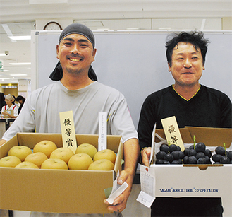 選ばれた果実を手に笑顔を見せる井上さん（左）と亀井さん