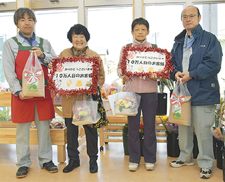 10万人目の荒井さんと藤原さんには花と座間のひまわり米が贈られた