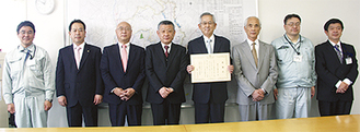 杉山所長（左から４人目）、感謝状を手にする浅岡理事長（同５人目）と組合員ら