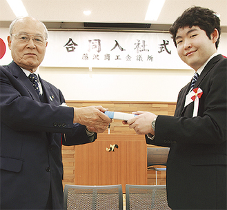記念品を手渡す田中会頭（左）と新入社員代表の安齊さん