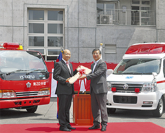 消防車両のレプリカキーを手にするチャウ・ソティラー参事官(左)と鈴木市長