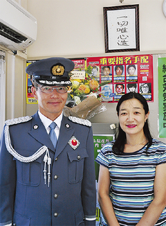 「県民の警察官章」を胸に付けた礼服姿の佐武さんと妻の博美さん。座右の銘「一切唯心造」を掲示している