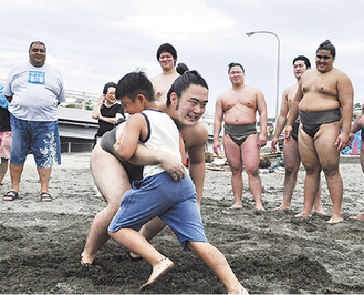「相撲などをきっかけに参加意欲が高まれば」と企画された。武蔵川親方（左）が見守る中、力士に飛び掛る少年
