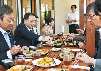 料理を試食する梶山担当相（左から２番目）